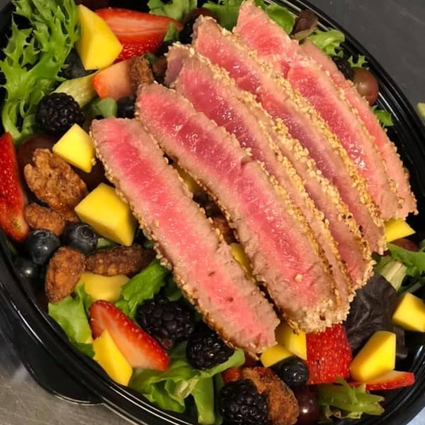 Seared tuna with sesame seeds, mixed greens, strawberries, mango, blueberries, and candied pecans.