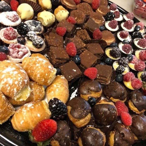 A platter of assorted Italian pastries, including chocolate brownies, cream puffs, and fruit tarts.