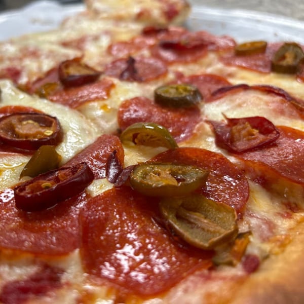 Close-up of a Cibo by Illiano pepperoni and jalapeño pizza slice with melted cheese.